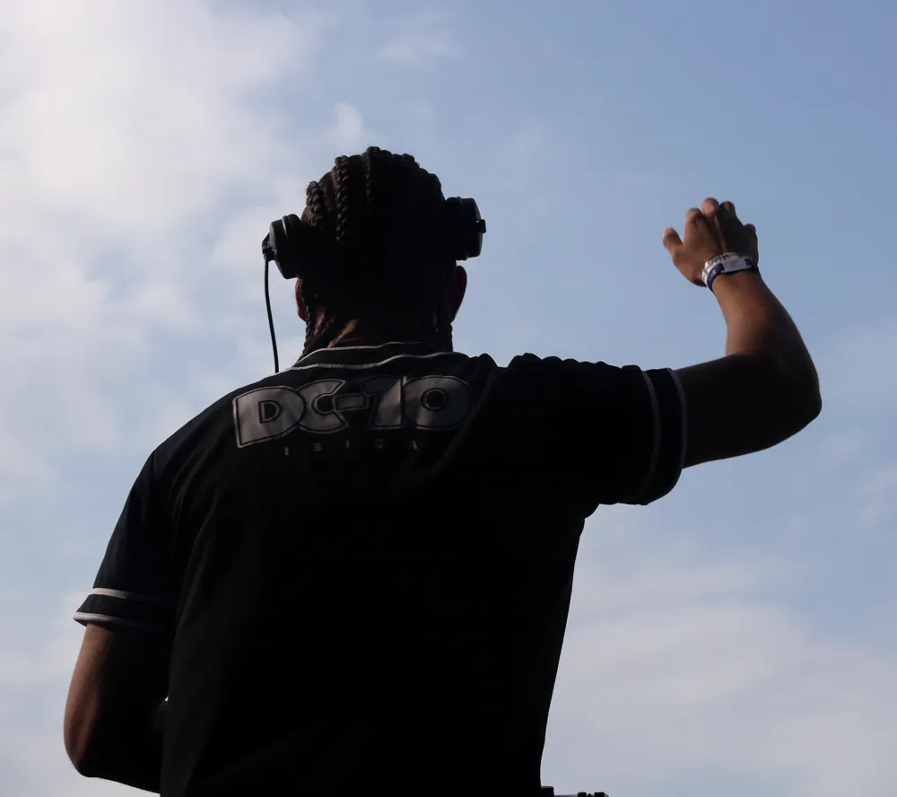 Silueta del DJ con el puño arriba contra el cielo