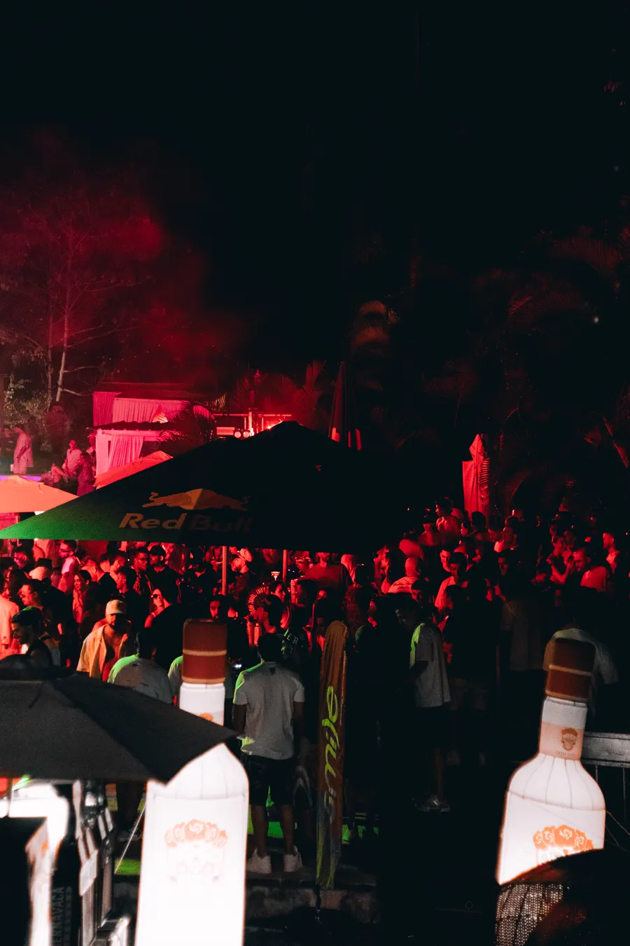 Multitud de noche bajo luz roja en Initium
